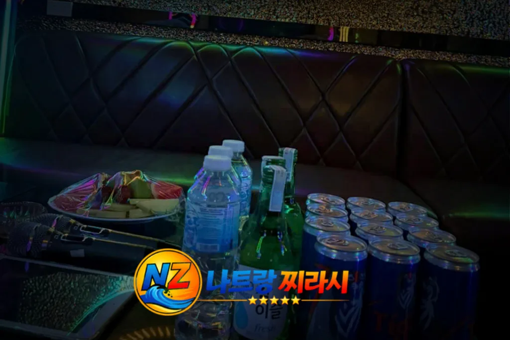 Club lounge table with water bottles, cans, and a plate of snacks on a dark leather bench; colorful logo in the foreground
